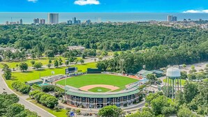 Un stade de baseball doté d’un grand terrain, entouré d’arbres et surplombé d’un château d’eau.