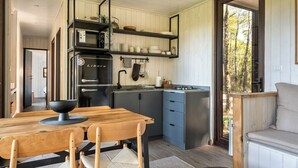 Una cocina moderna con una mesa de comedor de madera, electrodomésticos integrados y vistas a través de la puerta.