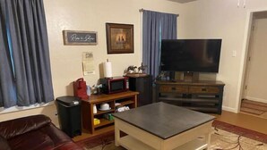 Una sala de estar con un sofá de cuero, una mesa de centro, un televisor, un microondas y un mueble bajo.