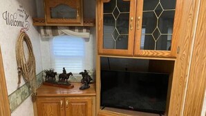 Un mueble de madera con un televisor y pequeñas figuras decorativas de caballos.