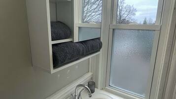 A bathroom with a white sink, a mirror, and a window.
