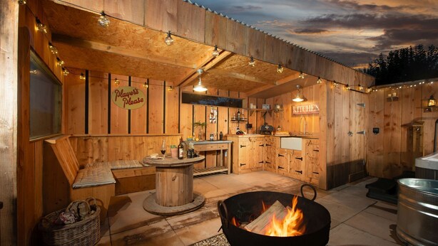 Un chalet rustique en bois, doté d’un coin bar, d’un foyer et d’une cuisine.