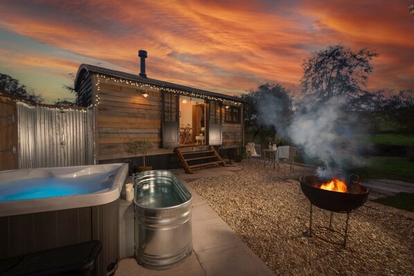 Une cabane en bois avec un bain à remous, un tonneau et un foyer.