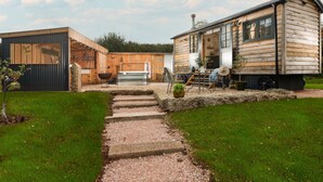 Une cabane en bois rustique comprenant un coin cuisine, une table à manger et un grand bac à plantes.
