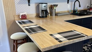 A kitchen with a wooden island, bar stools, a coffee maker, and a variety of kitchen utensils and appliances. - Meadow Farm-View Getaway (Sparta)