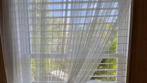 A bedroom with a window, a bed, and two potted plants on the windowsill. - Meadow Farm-View Getaway (Sparta)