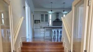 A wooden staircase leading to a kitchen with white cabinets and a central island.