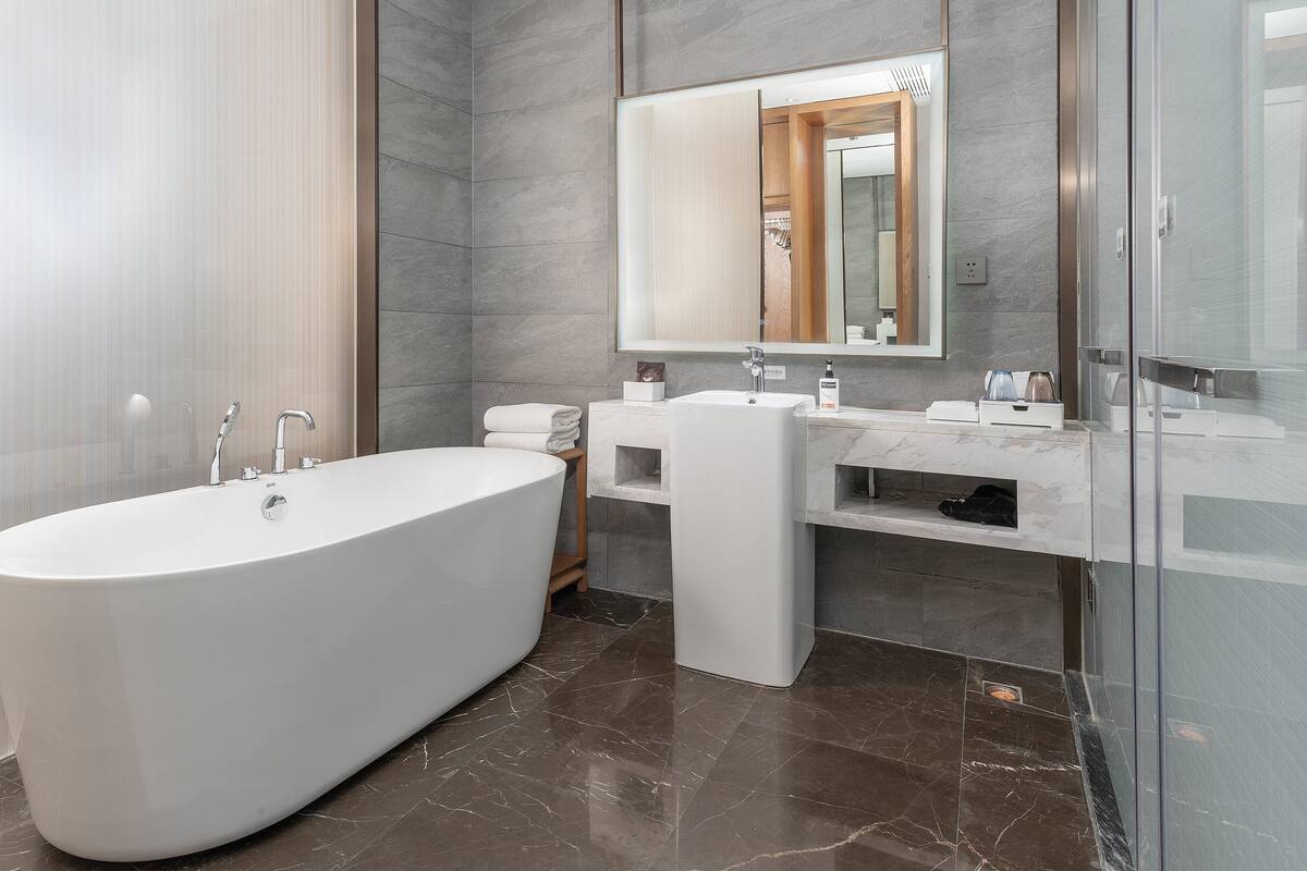 A modern bathroom with a freestanding bathtub, a vanity with a mirror, and a glass shower enclosure.