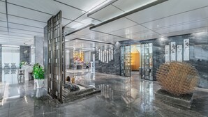 A modern lobby with a reflective marble floor, a reception desk, and a large decorative sphere. - Holiday Inn Express Pingchang by IHG (Bazhong)