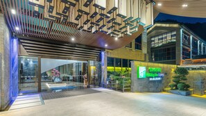 A hotel entrance with a modern design, featuring a glass facade, a wooden ceiling, and a sign indicating it is a Holiday Inn Express. - Holiday Inn Express Pingchang by IHG (Bazhong)