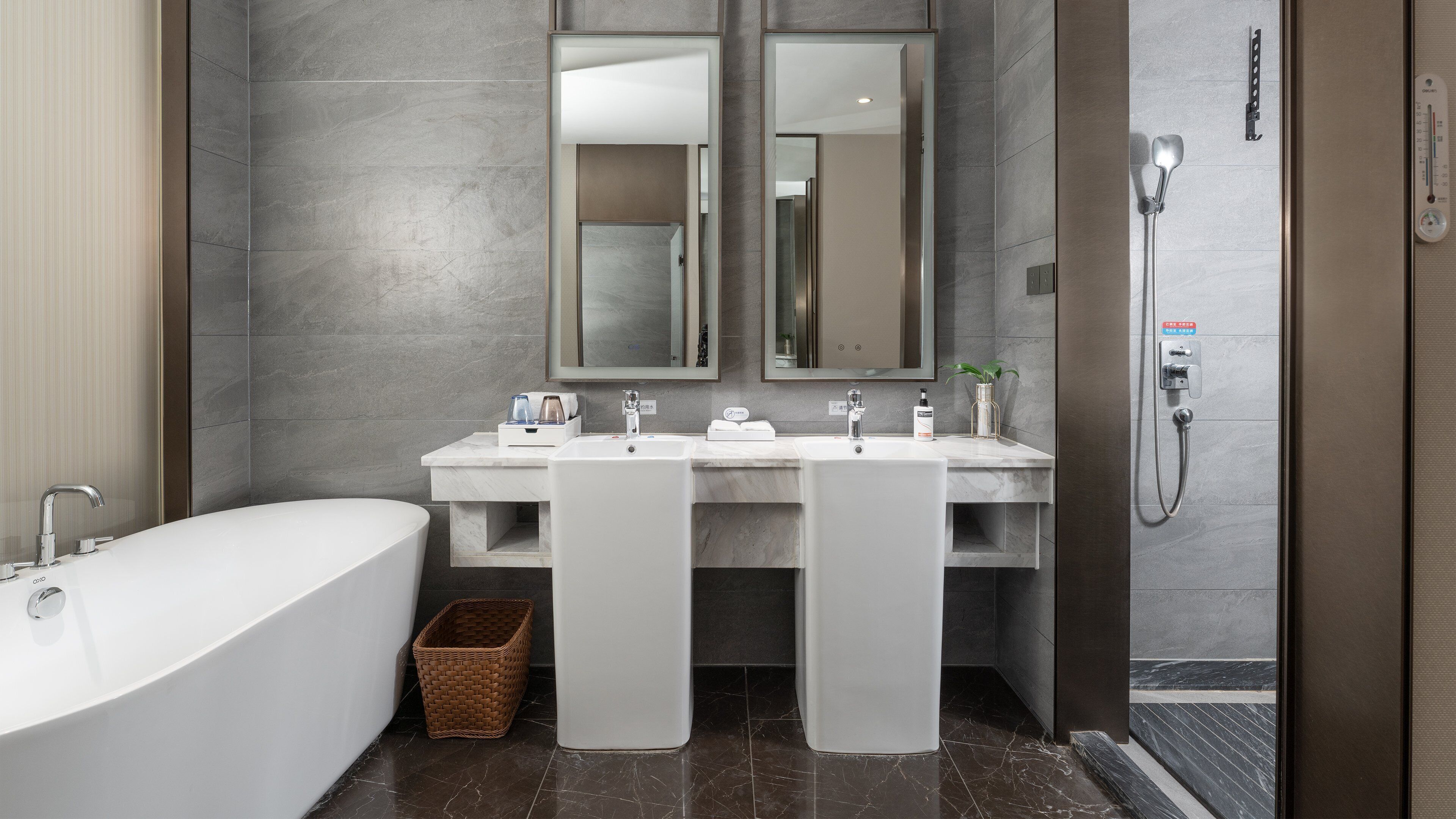 A modern bathroom with a freestanding bathtub, two sinks, and a walk-in shower.