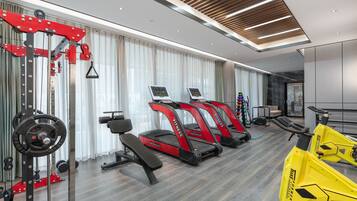 A modern gym with treadmills, weight machines, and a rowing machine.
