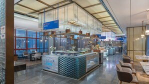 A modern restaurant with a high ceiling, large windows, and a central serving area with a marble counter. - Holiday Inn Express Pingchang by IHG (Bazhong)