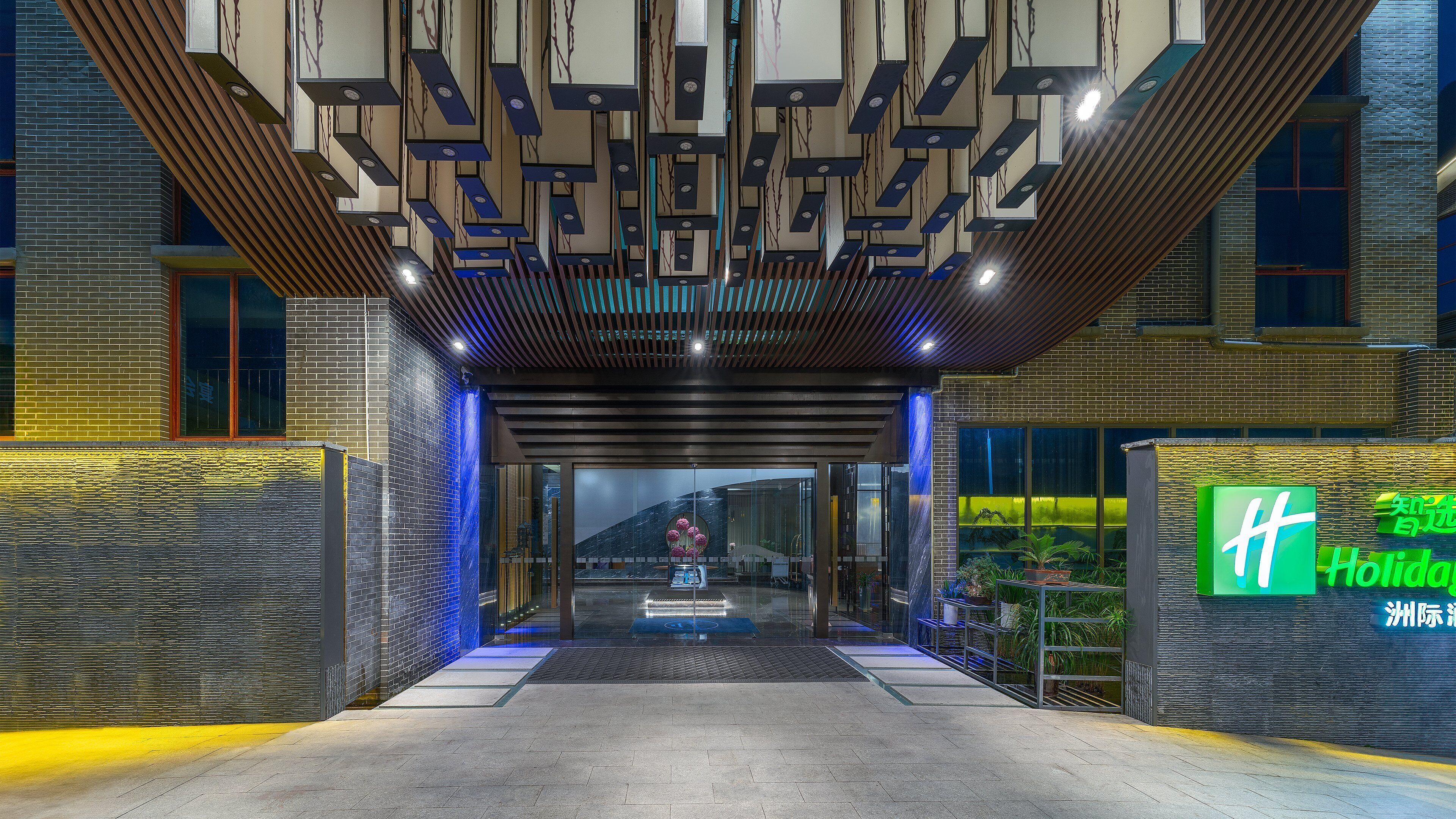 L'entrée d'un hôtel au design moderne, caractérisée par une façade en briques, une entrée en verre et une enseigne portant le nom de l'hôtel.