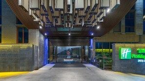 A hotel entrance with a modern design, featuring a brick facade, a glass entrance, and a signboard with the hotel name. - Holiday Inn Express Pingchang by IHG (Bazhong)