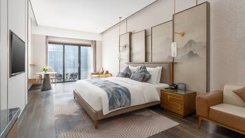 A modern hotel room with a large bed, a desk, a chair, a TV, and a view of the city.
