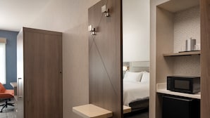 A hotel room with a bed, a microwave, a small refrigerator, a desk with a chair, and a wardrobe. - Holiday Inn Express & Suites Fresno Airport by IHG (Fresno)