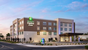 A Holiday Inn Express & Suites hotel with a modern design, featuring a prominent sign, a covered entrance, and a landscaped front yard. - Holiday Inn Express & Suites Fresno Airport by IHG (Fresno)