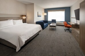 Habitación de hotel con una cama grande, un sofá, un escritorio y una silla.