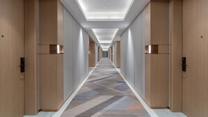 A hotel corridor with wooden doors, a patterned carpet, and recessed lighting. - Holiday Inn Express Quanzhou Taishang by IHG (Quanzhou)