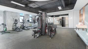 Un gimnasio con diversos equipos de ejercicio, incluyendo cintas de correr, elípticas y máquinas de pesas.