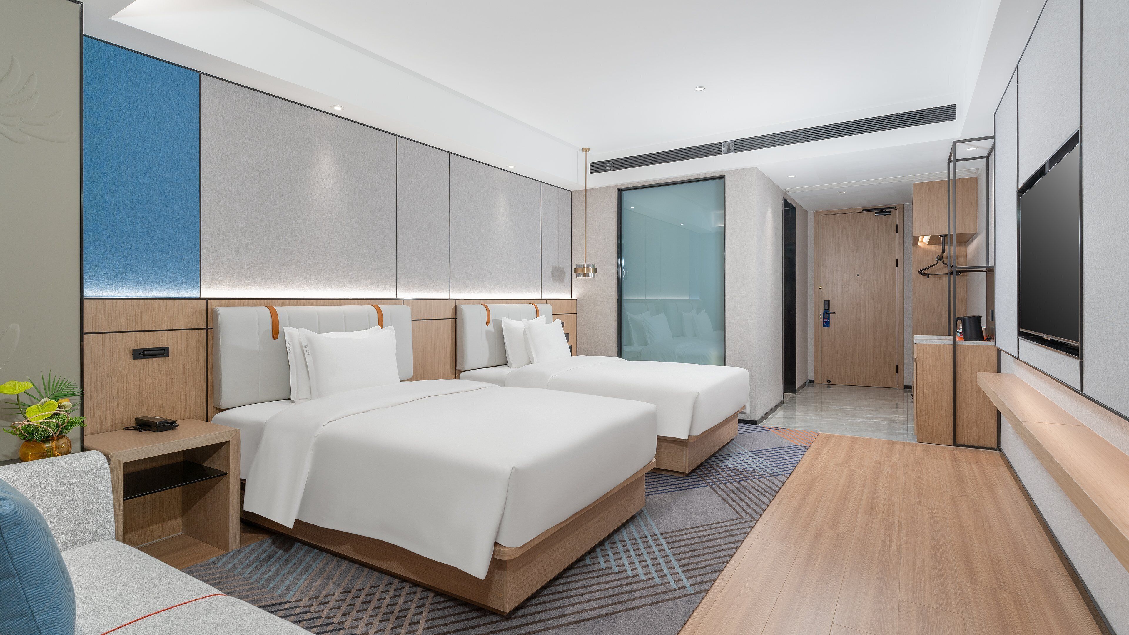 Ett modernt hotellrum med två sängar, en platt-TV, ett skrivbord och ett stort fönster.