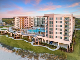 A modern hotel with multiple floors, a central pool area, and a landscaped garden.