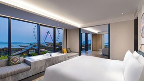 Une chambre d’hôtel moderne dotée d’un grand lit, d’un coin salon et offrant une vue sur une grande roue et des immeubles.