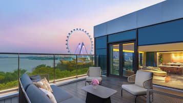 A modern outdoor balcony with a view of a Ferris wheel, seating, and a dining area.