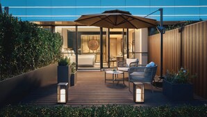 A modern outdoor patio with a wooden deck, seating area, and a large umbrella. - Hotel Indigo Suzhou Jinji Lake by IHG (Suzhou)