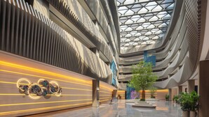 Un vaste atrium doté d’un haut plafond, d’une architecture moderne et d’un arbre central.