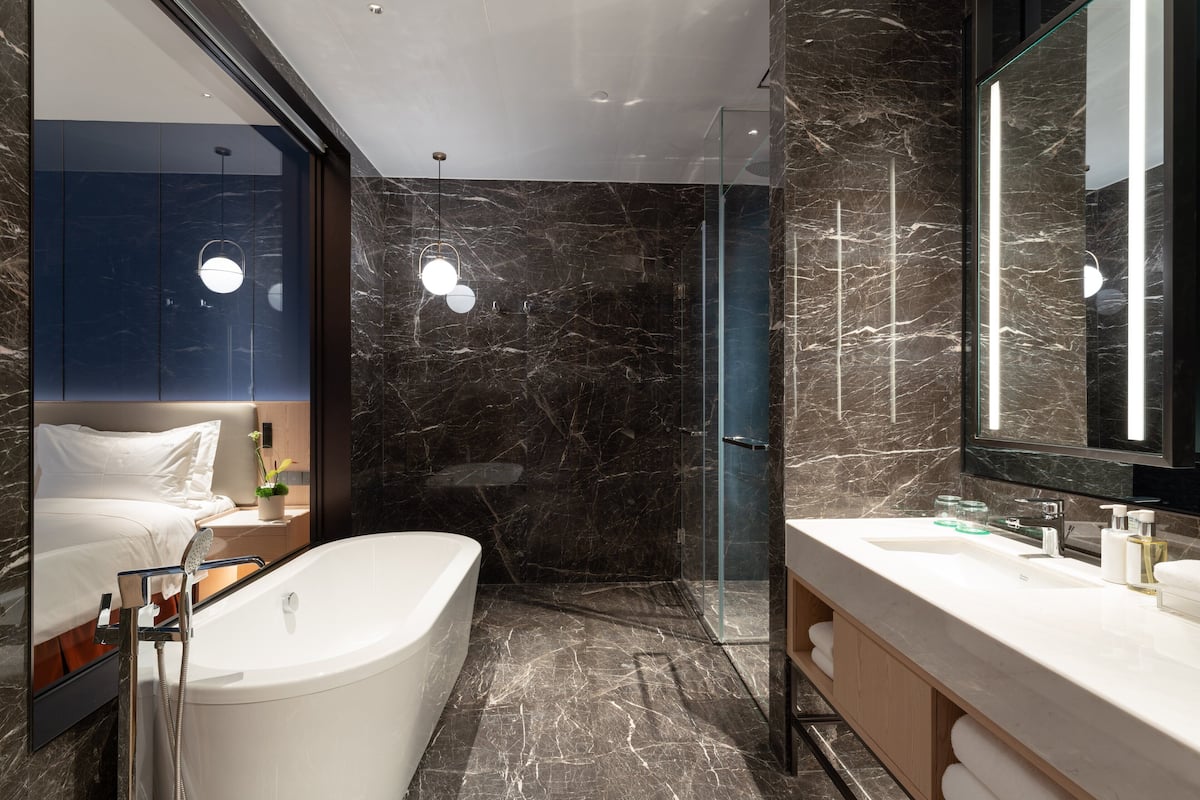 Ein modernes Badezimmer mit einer großen Badewanne, einer Duschkabine aus Glas und einem Waschtisch mit Spiegel.