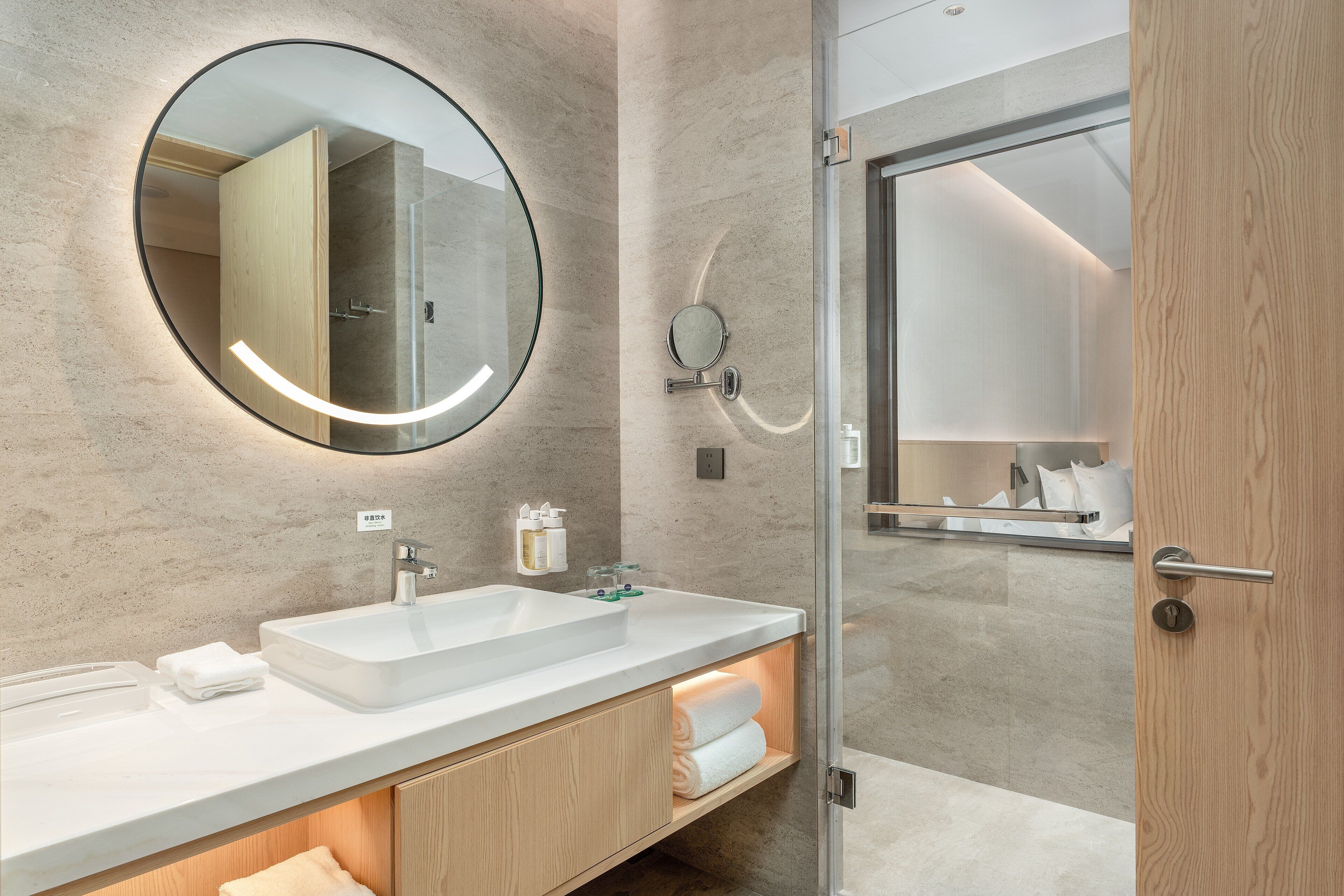 A modern bathroom with a large mirror, a double sink, and a wooden vanity.