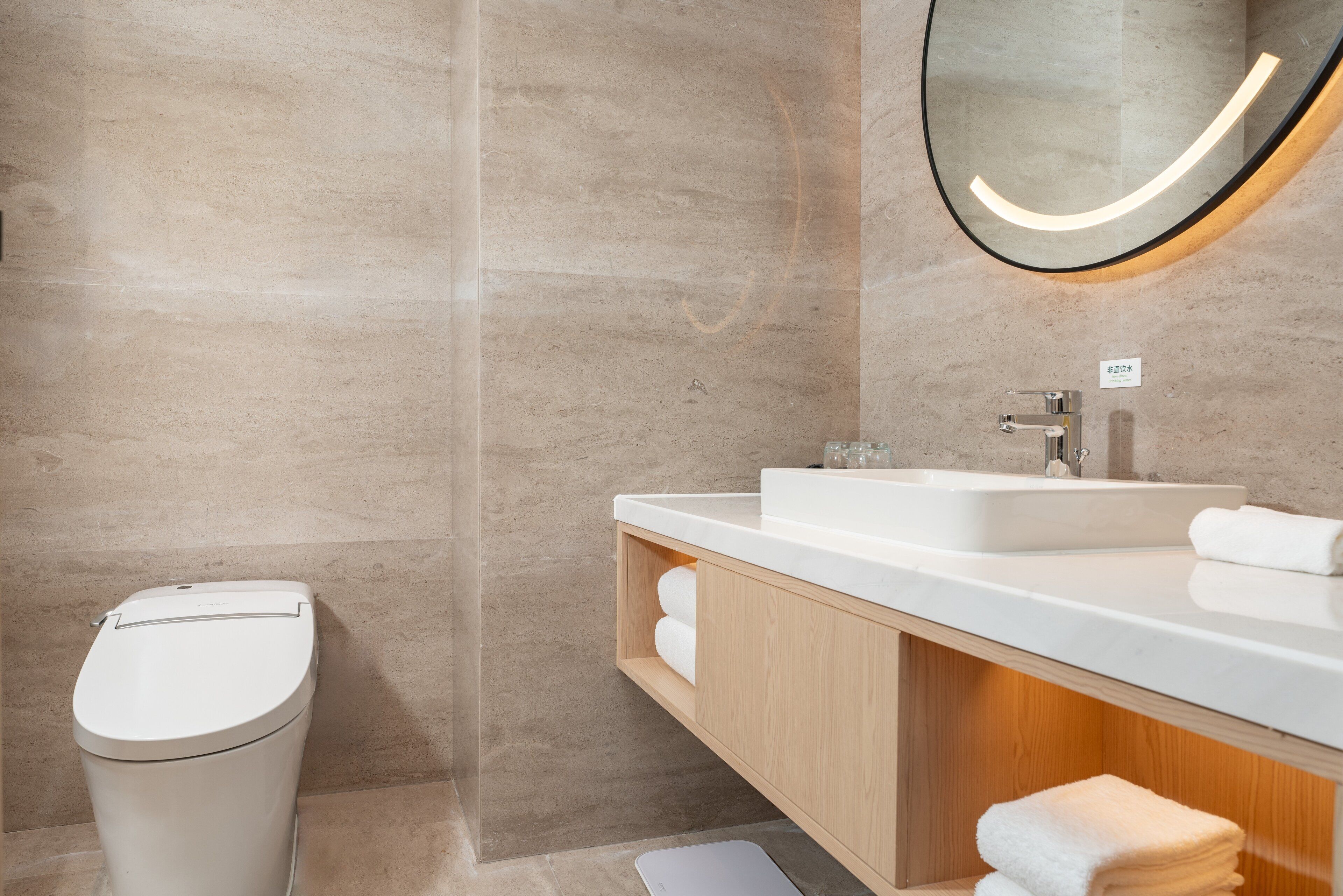 A modern bathroom with a toilet, a sink, and a mirror.