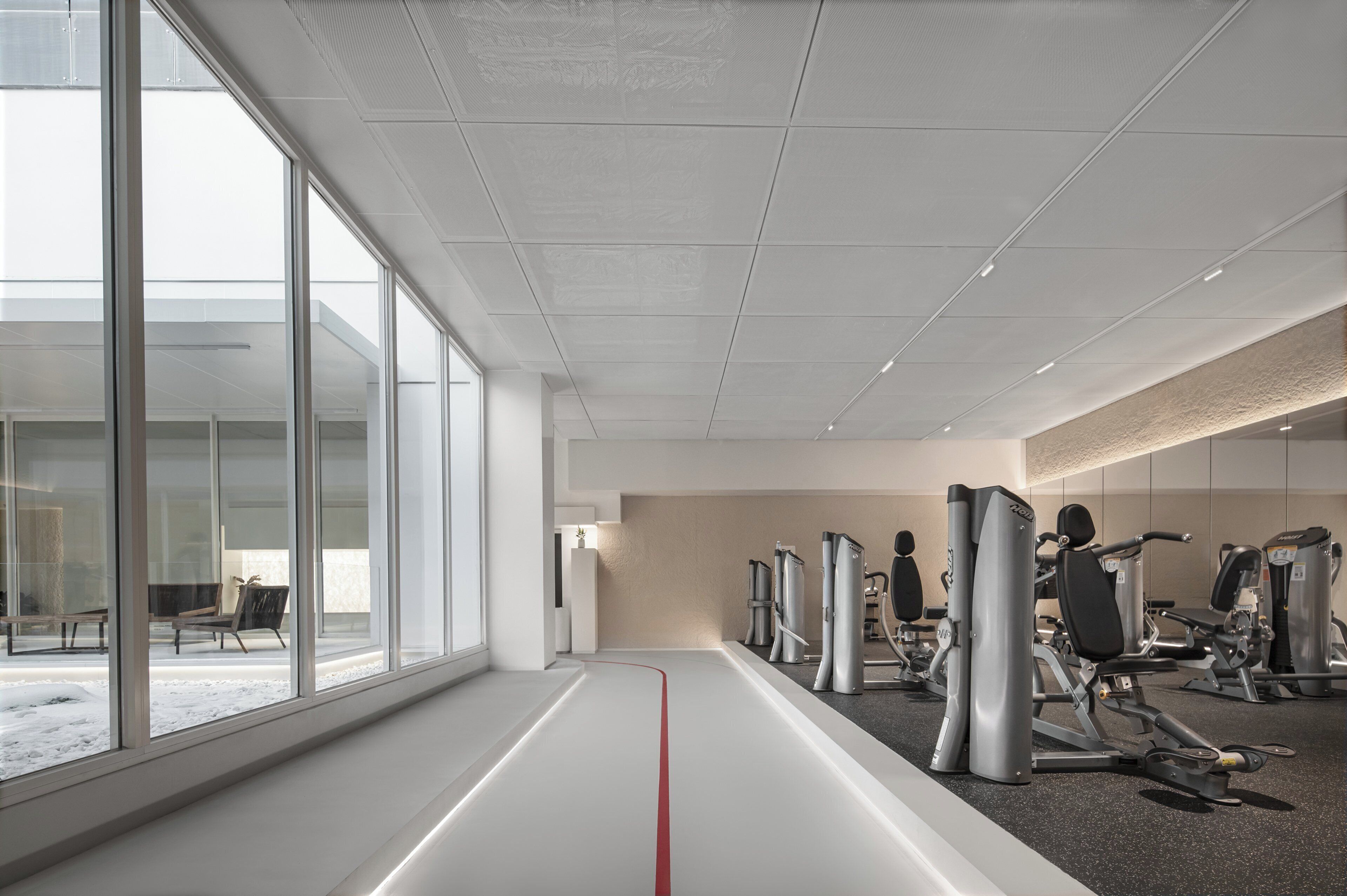 A modern gym with large windows, exercise equipment, and a minimalist design.