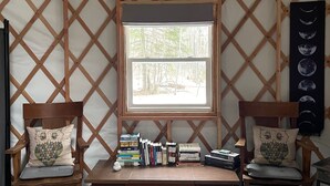 Un coin lecture confortable avec deux fauteuils en bois, un banc et une fenêtre donnant sur une forêt.