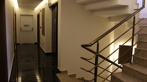 Un pasillo moderno de hotel con una escalera, una puerta y un letrero de salida de emergencia, además de una barandilla.