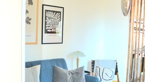 A living room with a blue sofa, a wooden coffee table, and framed artwork on the wall. - Wohnung am Bergpark Wilhelmshöhe (Kassel)