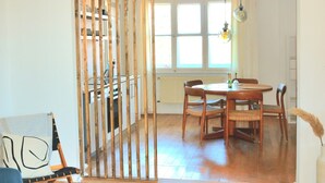 A dining area with a round table and chairs, a wooden partition, and a window with natural light. - Wohnung am Bergpark Wilhelmshöhe (Kassel)