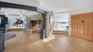 Un salón amplio con chimenea de piedra, un piano y una gran puerta de madera.