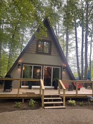 Eine moderne A-Form-Hütte mit einer Terrasse, großen Schiebetüren und einem kleinen Vorbereich.