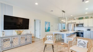 A modern kitchen with white cabinets, a large island, and a flat-screen TV. - Families w/ Pets! Ocean-View Crystal Beach Retreat (Crystal Beach)