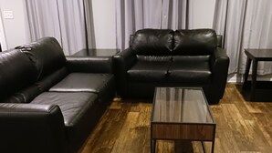 Olohuone, jossa on kulmasohva, sohvapöytä ja puulattia.