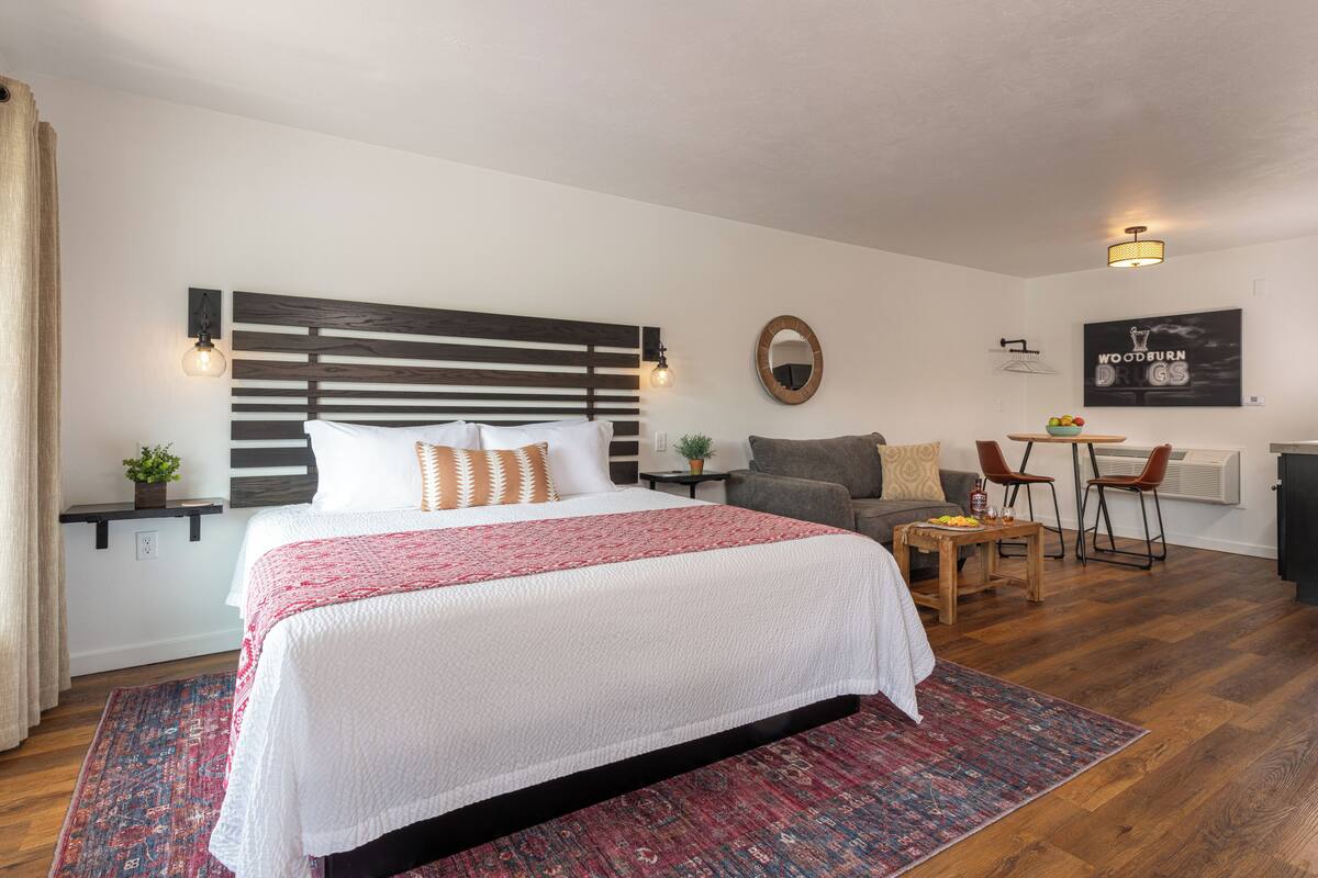 Ein modernes Hotelzimmer mit einem großen Bett, einem kleinen Schreibtisch, einer Couch und einem Esstisch.