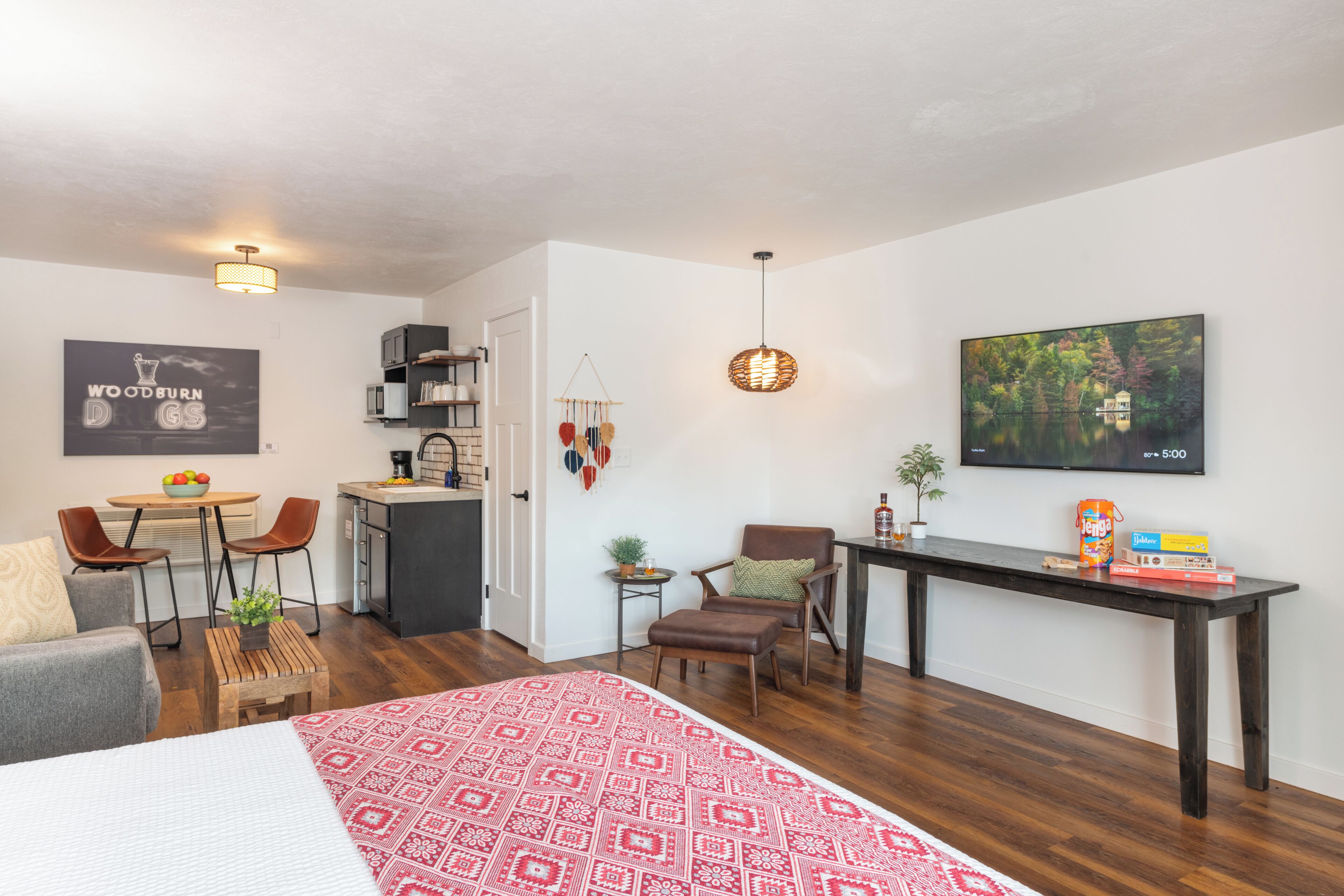 Una habitación moderna y bien iluminada con cama, comedor, cocina y zona de estar con vistas a un lago.