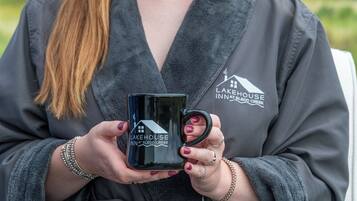 Eine Person hält eine schwarze Tasse mit dem Schriftzug 'Lakehouse Inn at Sledd Creek'.