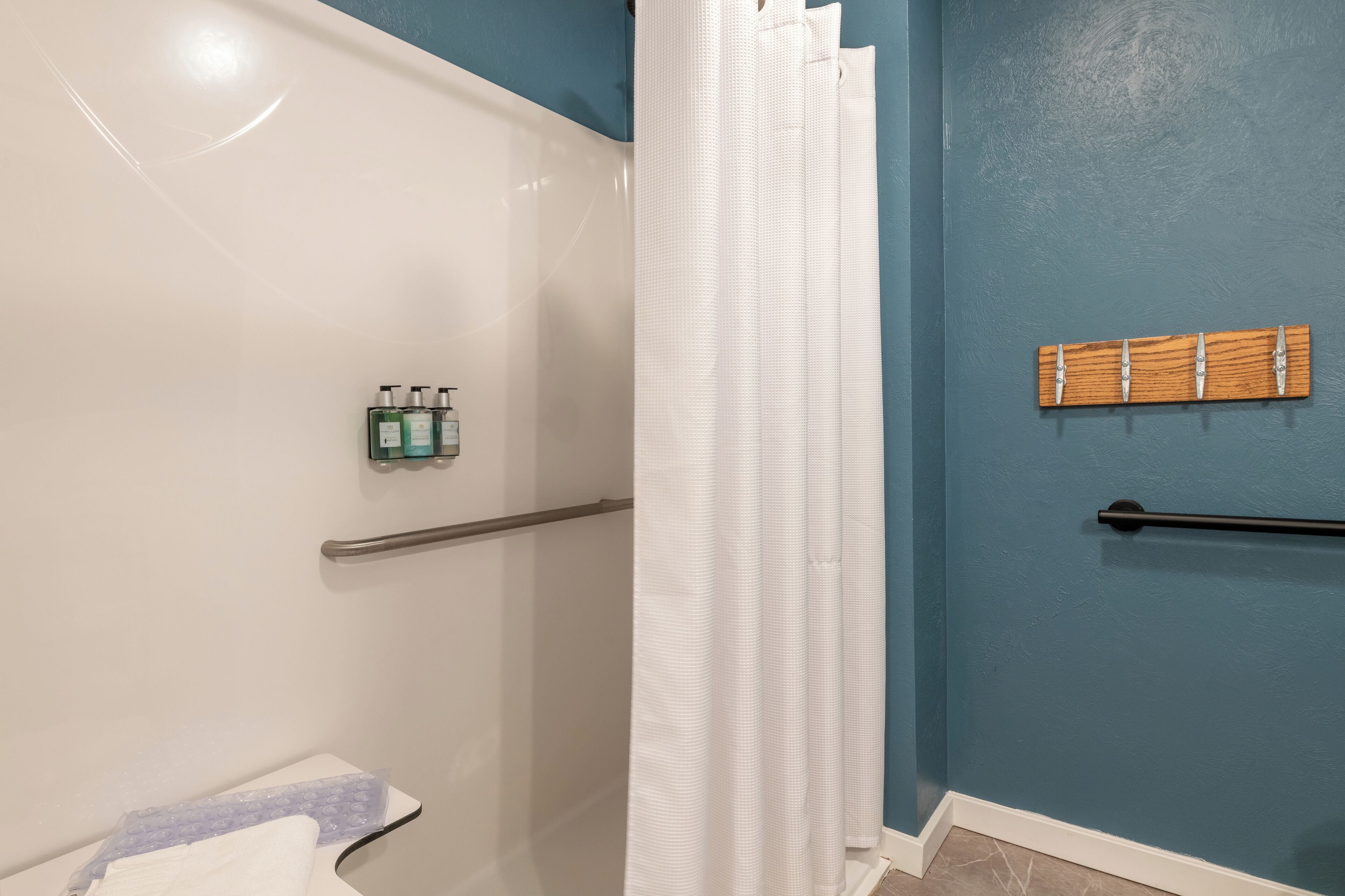 Un baño con ducha, toallero y artículos de aseo en la pared.