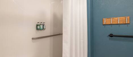 Un baño con ducha, toallero y artículos de aseo en la pared.