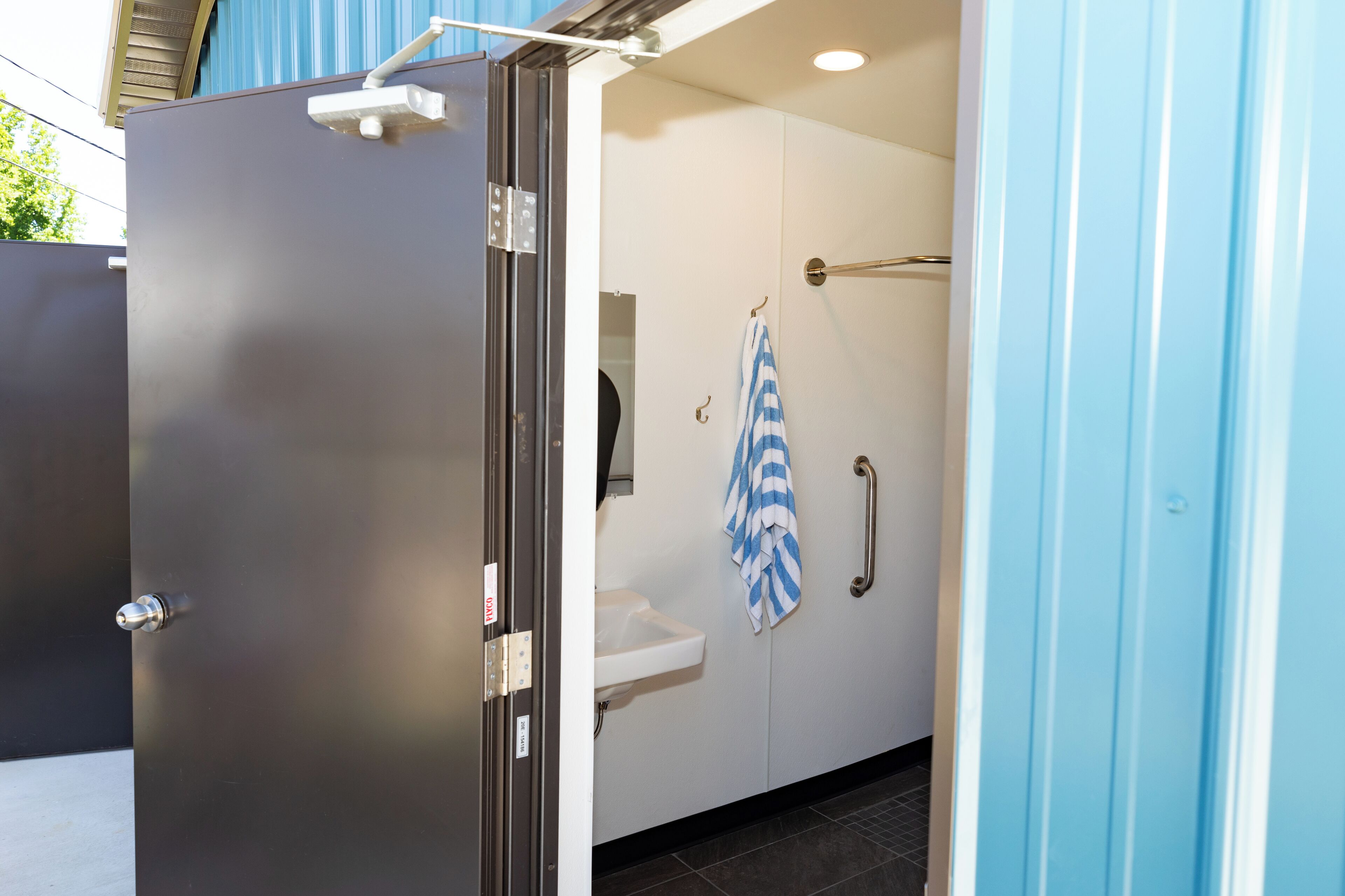 A bathroom with a shower, a sink, and a towel hanging on a rack.