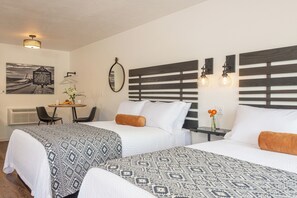 Ein Hotelzimmer mit zwei Betten, einem kleinen Tisch mit Stühlen, einem Spiegel und einer Wandleuchte.